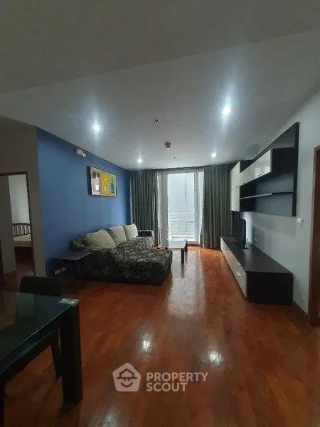 Spacious living room with modern decor and wooden flooring, featuring a large sofa and entertainment unit.