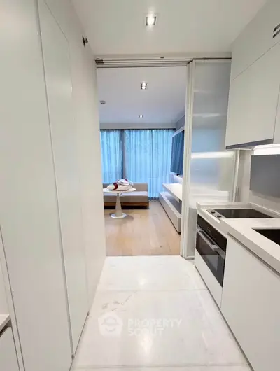 Modern open-layout kitchen leading to a stylish living room with large windows and natural light.