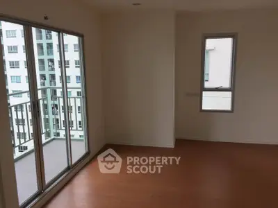 Spacious empty room with balcony access in modern apartment building.