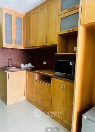 Modern kitchen with wooden cabinets and built-in microwave in a cozy apartment.