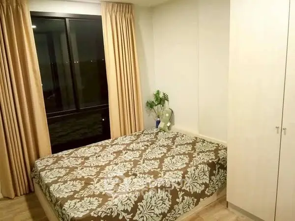 Cozy bedroom with large window and elegant curtains, perfect for relaxation.