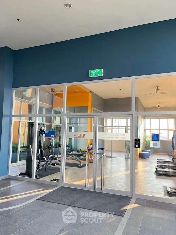 Modern gym with glass entrance and fitness equipment in a residential building.