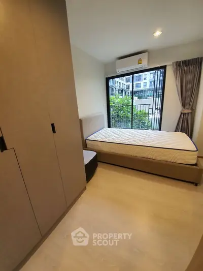 Cozy bedroom with large window and modern furnishings in a stylish apartment.