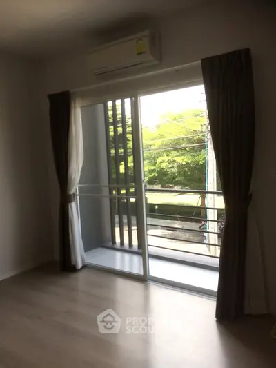 Bright room with large window and balcony view, featuring elegant curtains and air conditioning.