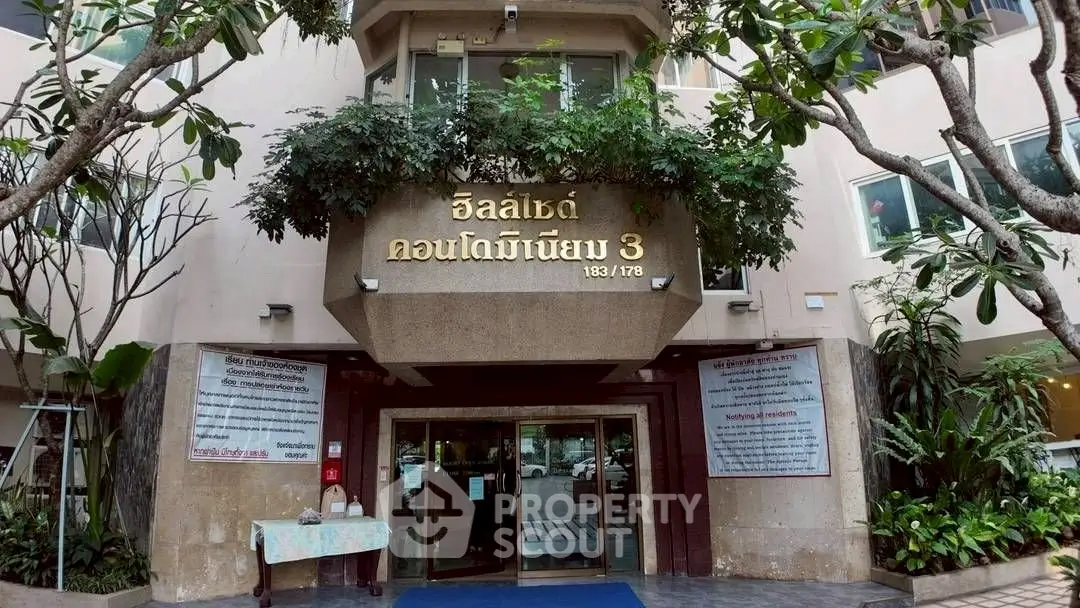 Elegant entrance of a modern condominium with lush greenery and welcoming ambiance.