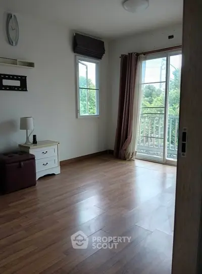 Spacious room with wooden flooring and balcony view, ideal for modern living.