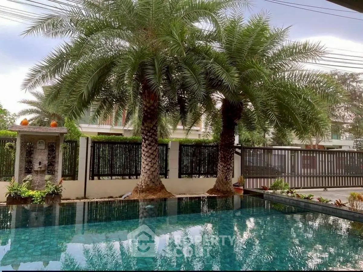 Luxurious poolside view with palm trees in a serene residential setting.