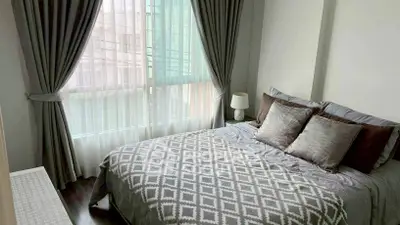 Cozy bedroom with elegant curtains and stylish bedding in a modern apartment.