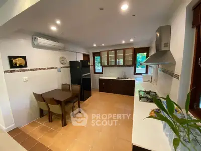 Spacious kitchen with modern appliances and open layout, featuring a dining area and large windows for natural light.