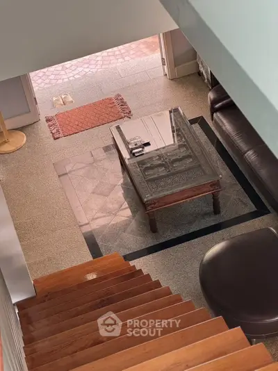 Stylish living room with elegant wooden stairs and glass coffee table