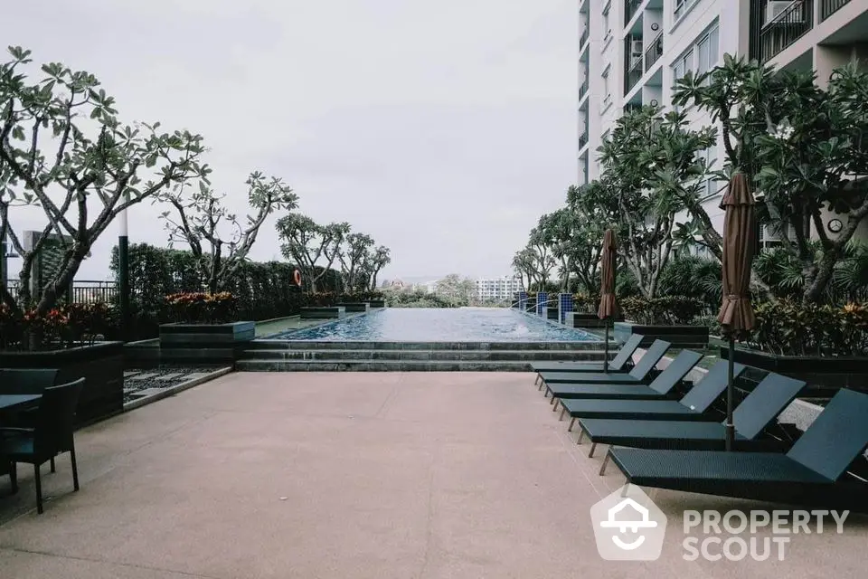 Luxurious condominium pool area with sun loungers and lush greenery