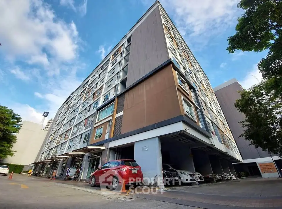 Modern multi-story apartment building with parking and clear blue sky.