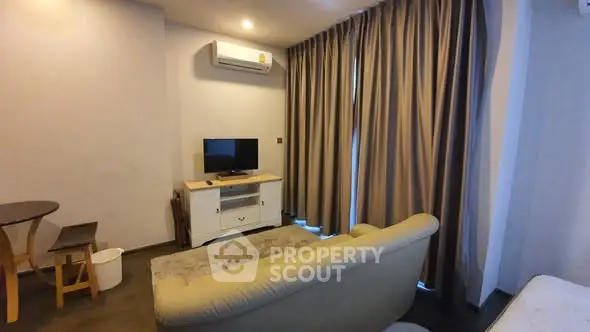 Cozy living room with modern decor and natural light, featuring a comfortable sofa and a flat-screen TV.