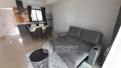 Modern living room with sleek furniture and open kitchen layout in a stylish apartment.