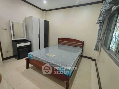 Spacious bedroom with modern furniture and large window for natural light.