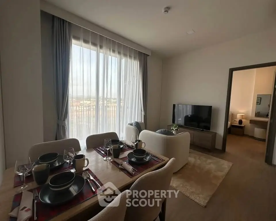 Modern living room with dining area and large window offering natural light.