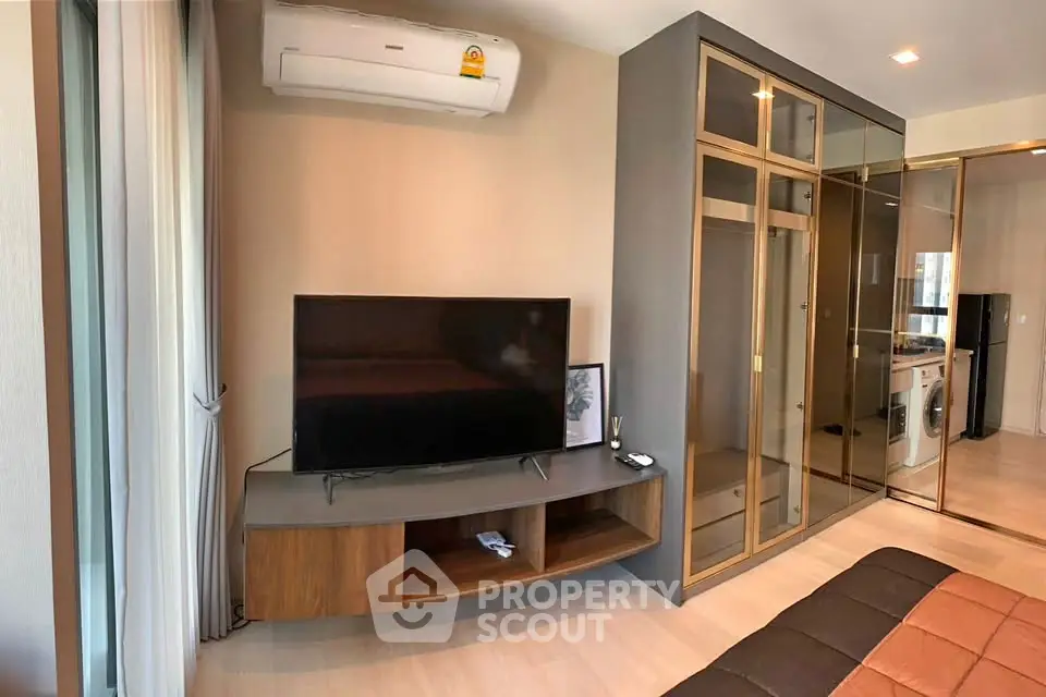 Modern bedroom with TV, air conditioning, and mirrored wardrobe in stylish apartment.