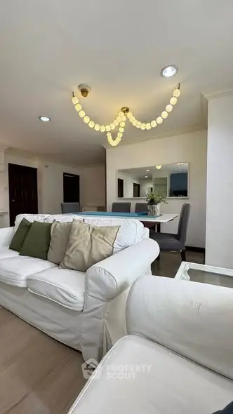 Spacious living room with elegant chandelier and cozy seating area in modern apartment.