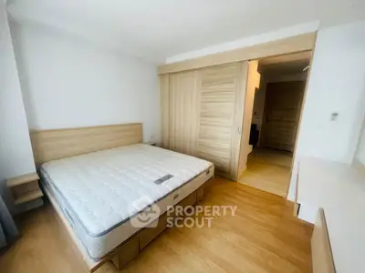 Modern bedroom with wooden flooring and built-in wardrobe, featuring a comfortable bed and minimalist design.