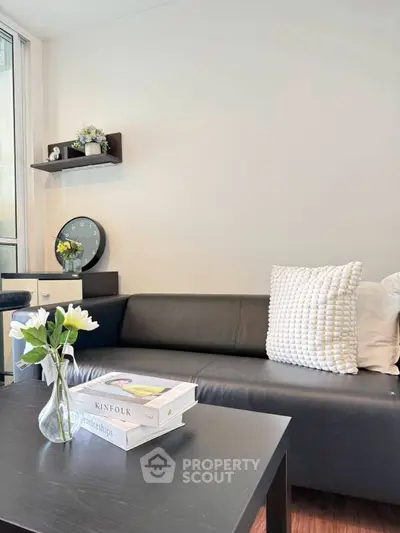 Modern living room with sleek black sofa, stylish decor, and natural light for a cozy ambiance.