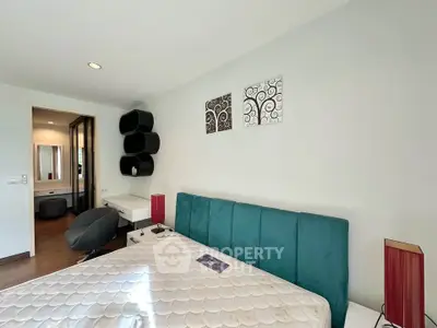 Modern bedroom with stylish decor and teal headboard, perfect for a cozy retreat.