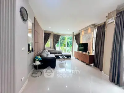 Spacious modern living room with elegant decor and large windows offering lush garden views.