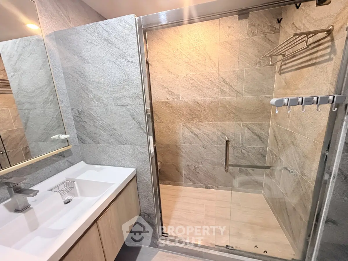 Modern bathroom with glass shower and sleek vanity in luxury apartment
