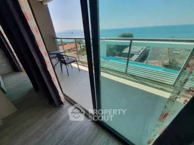 Stunning ocean view from modern balcony with glass railing and outdoor seating.