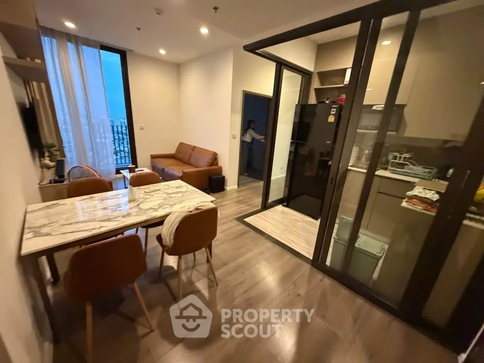 Modern apartment with open layout kitchen and cozy living area, featuring stylish furniture and large windows.