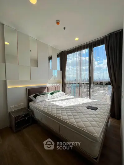 Modern bedroom with large windows offering stunning city views and elegant decor.