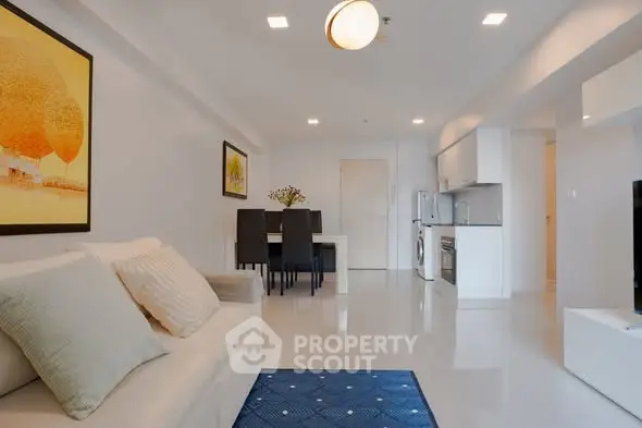 Modern living room with sleek furniture and open kitchen layout in a bright apartment.