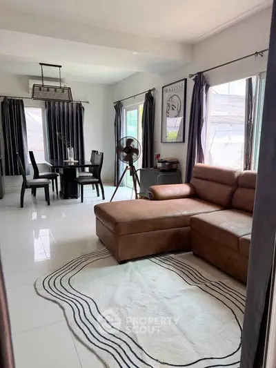 Spacious living room with modern decor and dining area, featuring large windows and stylish furniture.