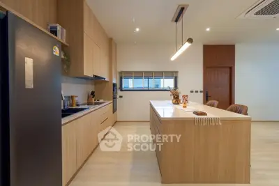 Modern kitchen with sleek wooden cabinetry and island, featuring open layout and contemporary lighting.