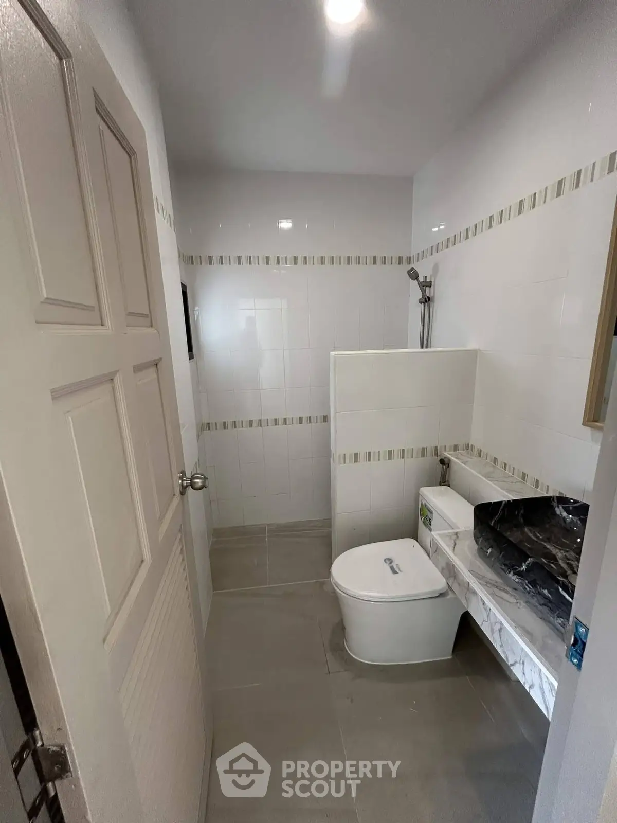 Modern bathroom with sleek design and neutral tones, featuring a compact layout and contemporary fixtures.
