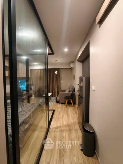 Modern apartment interior with glass partition, cozy living area, and sleek kitchen appliances.