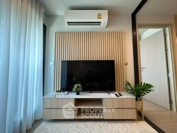 Modern living room with sleek TV setup and air conditioning, featuring stylish decor and natural light.