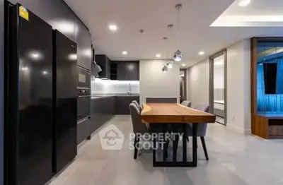 Modern kitchen with sleek black appliances and stylish dining area