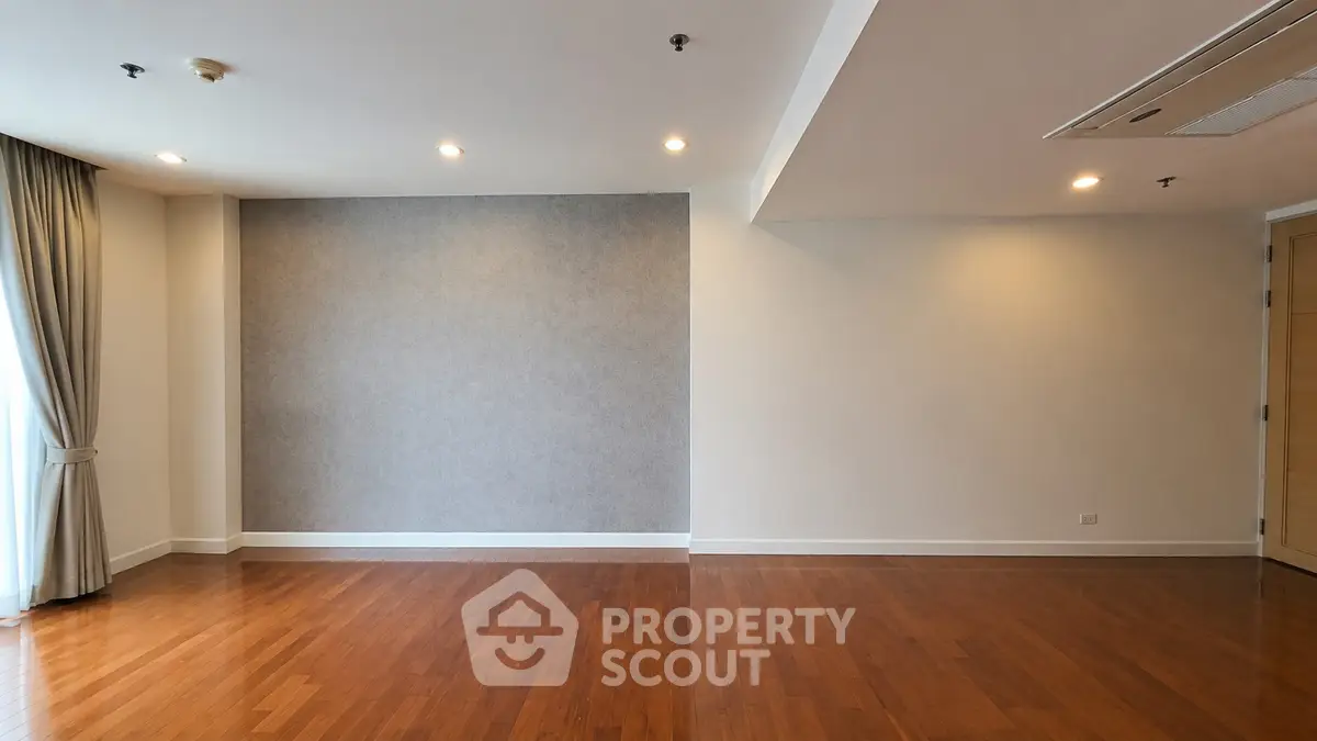 Spacious empty living room with hardwood floors and modern lighting