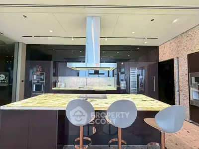 Luxurious modern kitchen with sleek design and high-end appliances, featuring a large island and stylish bar stools.