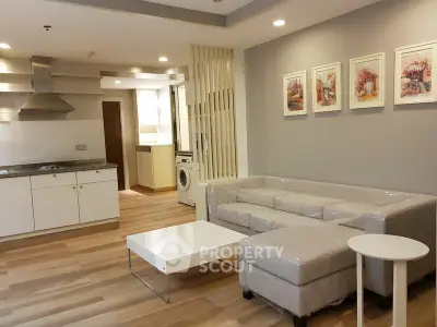 Modern open-layout living room with kitchen, featuring sleek furniture and stylish decor.