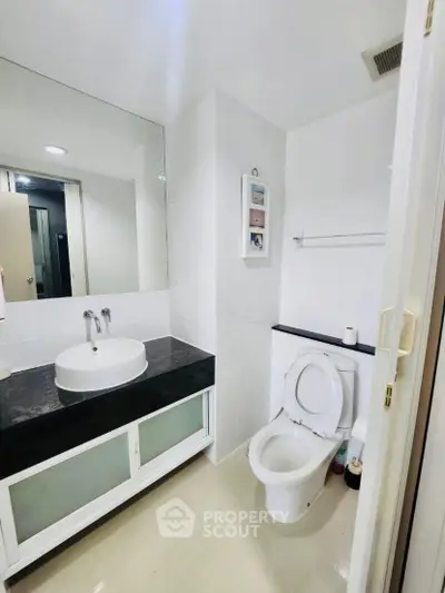 Modern bathroom with sleek white fixtures and large mirror in a contemporary home.