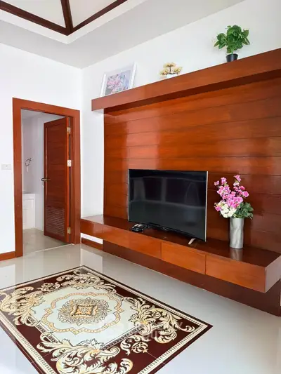 Elegant living room with wooden accent wall, modern TV setup, and decorative rug, perfect for cozy family gatherings.