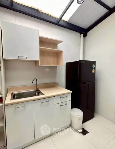 Modern kitchen with sleek cabinetry and black refrigerator in bright space.