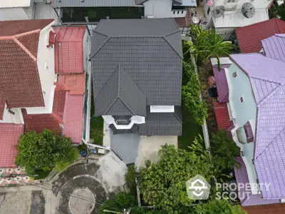 Aerial view of a modern house with a sleek black roof surrounded by colorful neighboring homes.