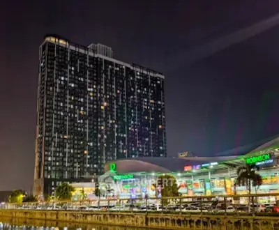 Stunning night view of a modern high-rise building with adjacent shopping center, perfect for urban living.