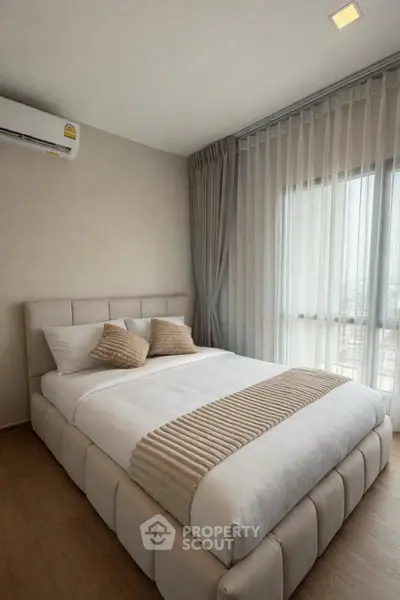Modern bedroom with large window and stylish decor in a high-rise apartment.