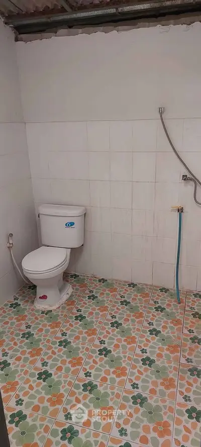 Simple bathroom with colorful tiled floor and basic fixtures.