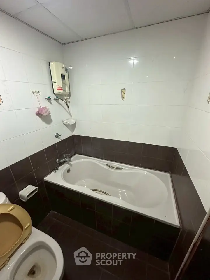 Compact bathroom with bathtub and tiled walls, featuring a simple and functional design.