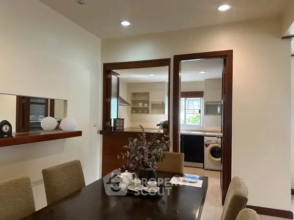 Elegant dining area with view into modern kitchen featuring washing machine.