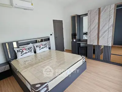 Modern bedroom with stylish furniture and wooden flooring, featuring a sleek wardrobe and comfortable bed.